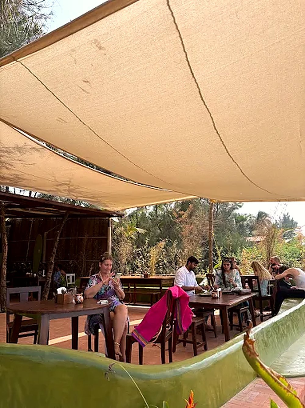 The dining room under a canvas roof, opening to the garden