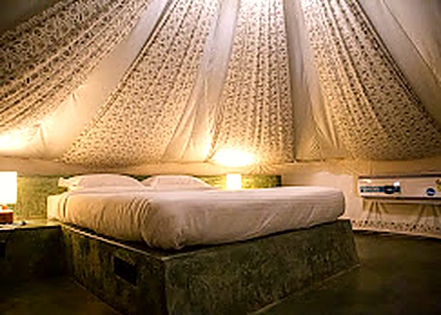 A made bed under the canvas of a Virama tent