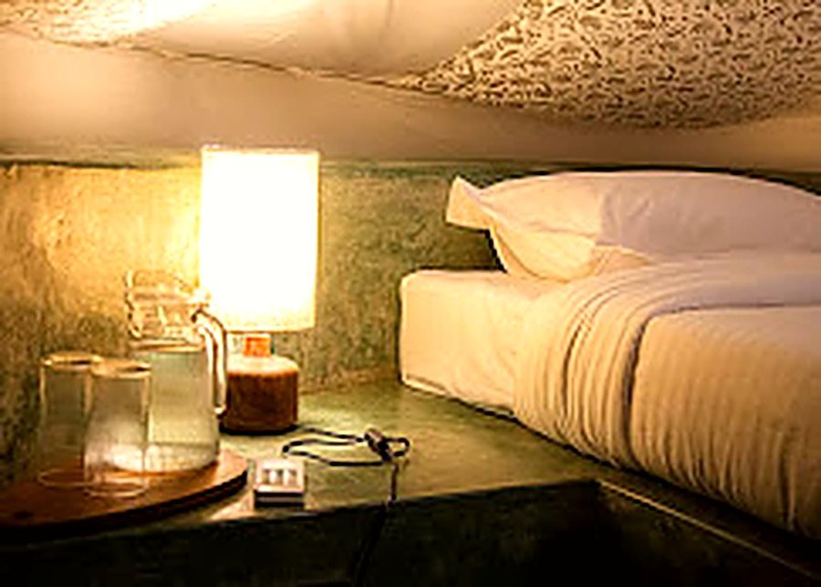 A bed and a warm lamp inside a Virama tent